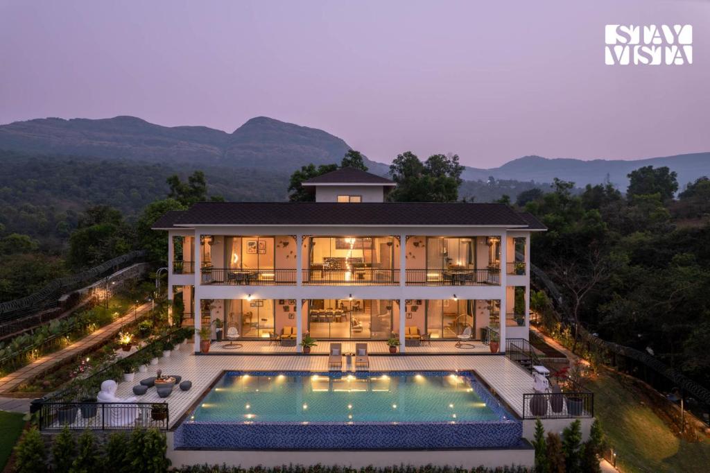 The retreat villa at twilight, its illuminated pool glowing against the Pawna hills